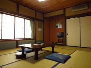 高山四反田日式旅馆的客厅配有桌子和电视