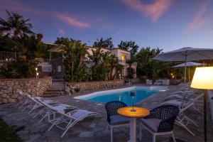 阿纳卡普里Capri Blue Luxury Villa Le Tre Monelle的一个带椅子和桌子的游泳池以及一把遮阳伞
