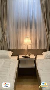 马卡尔斯卡Gabrijel Apartments Makarska 1的客房设有两张床和一张带台灯的桌子。