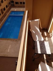 马拉喀什Agréable appartement au coeur de Guéliz, Marrakech的一个带椅子和游泳池的阳台