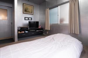 冈山Unique joy House的卧室配有白色的床和电视。