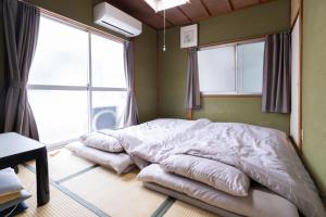 冈山Unique joy House的一张位于带两个大窗户的房间的床铺