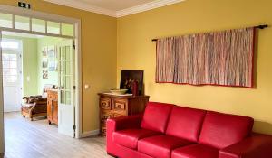 奥尔塔Casa da Japoneira的客厅里的一个红色沙发,带有窗户