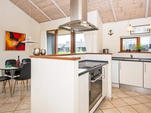 托斯明德8 person holiday home in Ulfborg的厨房配有白色橱柜、桌子和炉灶。