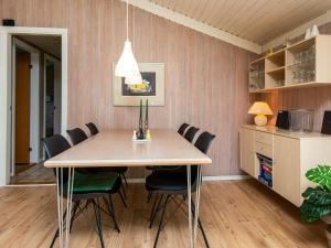 海默特6 person holiday home in Hemmet的一间带木桌和椅子的用餐室