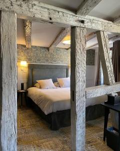 希伯维列Hôtel-Restaurant du Mouton的一间卧室设有一张带木梁的大床