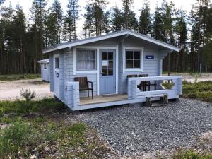 科林基拉Koli caravan cottages的一个小白色棚子,设有门廊和两把椅子