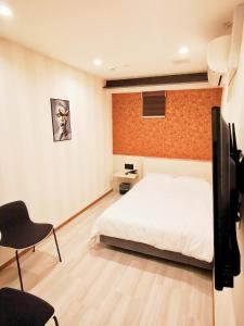 埼玉市Hotel mond omiya的一间卧室配有一张床、一台电视和一把椅子