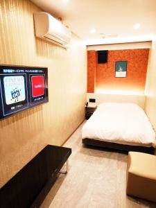 埼玉市Hotel mond omiya的卧室配有一张床,墙上配有电视。