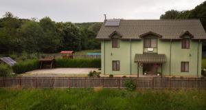 LuncaviţaAgropensiunea Cetatuia的前面有栅栏的绿色房子