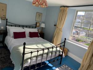 布鲁顿Charming townhouse in Bruton的一间卧室配有一张带红色枕头的床和一扇窗户