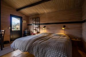 SevelHedelandets Camping的卧室配有一张床铺,位于带木墙的房间内