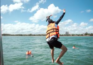 沙美岛沙美岛君怡度假酒店的背上一只狗跳入水中的人