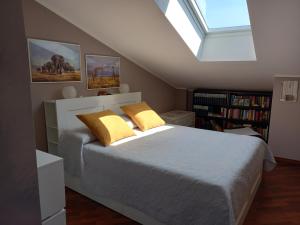 博拉泰La mansarda di Mi&Lo junior suite的一间卧室配有一张带黄色枕头的床和一扇窗户