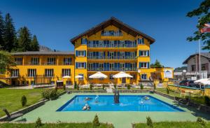 帕尔潘Grischalodge das Hotel mit Bergblick seit 1929的大楼前设有游泳池的酒店