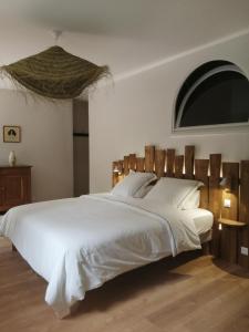 PersacChambres d'hôtes de la pilatière的卧室配有一张白色大床和木制床头板