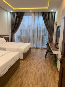 绥和市Minh Hoàng Hotel的酒店客房设有两张床、一张书桌和一个窗户。