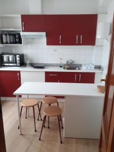 卡尔达斯·德·雷斯Pensión Río Umia的厨房配有红色橱柜、白色桌子和凳子