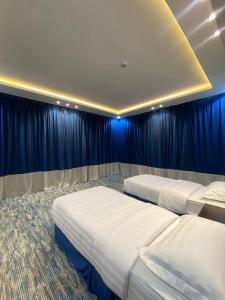 艾卜哈قمم بارك Qimam Park Hotel 2的配有蓝色窗帘的客房内的两张床