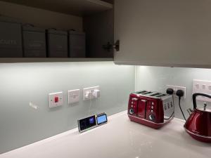 伦敦Modern & Spacious Penthouse in North London的厨房柜台配有红色烤面包机和两个时钟