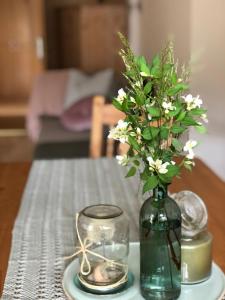 ReisachFerienhaus Mautzfried的绿花瓶,桌子上放着白色花