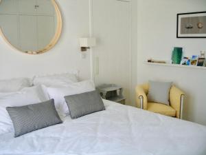 里夫杜海滩Le Clos des Fantaisies的卧室配有一张带镜子和椅子的白色床
