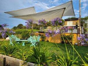 坦迪尔al pie de las sierras en villa del lago的一座种有紫色花卉和白色遮阳伞的花园
