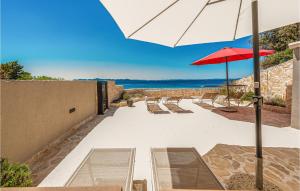 佩特坎内Beach Front Apartment In Petrcane With Kitchen的一个带长椅和遮阳伞的庭院和大海