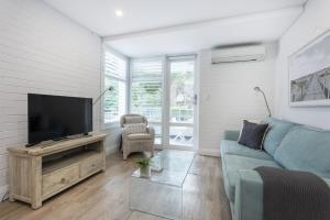 珀斯Cottesloe Beach View Apartment - EXECUTIVE ESCAPES的客厅配有蓝色的沙发和平面电视。