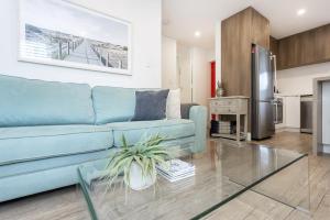 珀斯Cottesloe Beach View Apartment - EXECUTIVE ESCAPES的一间带蓝色沙发的客厅和一间厨房