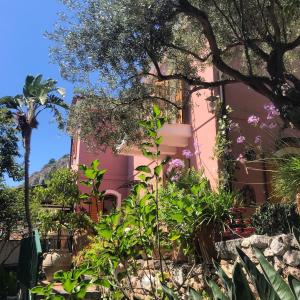 陶尔米纳不列颠尼亚度假屋的前面有植物的粉红色建筑