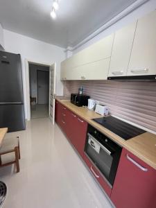 马马亚Mamaia Beach LuxyMar 3 Apartment的厨房配有红色橱柜和黑色冰箱