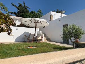 科斯镇Moeses House的白色的房子,配有桌子和雨伞