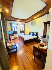 琅勃拉邦Luang Prabang Maison Vongprachan & Travel的大房间设有一张床铺和一张桌子