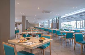 滨海罗克塔斯Hotel Roquetas El Palmeral by Pierre & Vacances的用餐室配有桌椅和酒杯