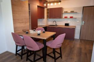 克卢日-纳波卡BG LUXIMMO APARTMENTS的厨房配有木桌和粉红色的椅子