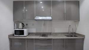 科威特BHomed Furnished Apartments的厨房配有不锈钢橱柜和微波炉