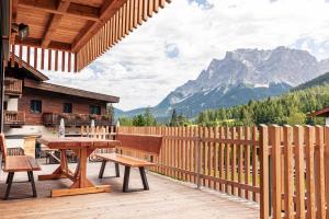 比伯维尔Alpenchalets Biberwier Zugspitze by ALPS RESORTS的木甲板上设有桌子、长凳和山脉