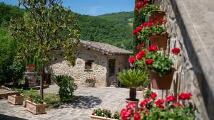 佩鲁贾Agriturismo I Pietrini的一座种有红色花卉和石头建筑的花园