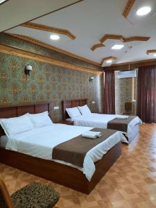 第比利斯Hotel LU-MA的一间卧室设有两张床和一堵带绿色壁纸的墙