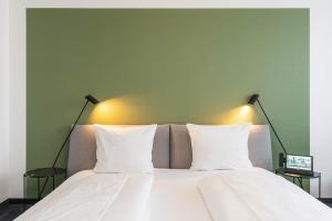 弗雷兴弗雷兴霍夫酒店的一张带两个白色枕头和绿色墙壁的床