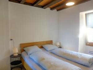 GrimisuatApartment Tilleul by Interhome的配有2张床的白色墙壁和窗户。