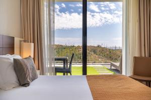 蒙希克Monchique Resort & Spa的酒店客房设有一张床和一个大窗户