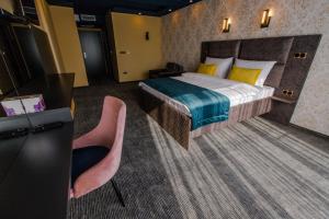 比哈奇HOTEL LOBBY的酒店客房,配有一张床和两张粉红色的椅子