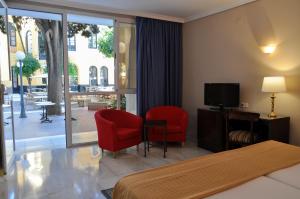塞维利亚圣吉尔酒店的酒店客房设有2把红色椅子和电视