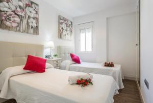 加的斯Ático Avda Cádiz Playa的宿舍间内的两张床,配有红色枕头