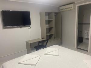 伊瓜苏Pousada Maria`s Inn - Conforto, acolhimento e qualidade em Foz do Iguaçu的一间卧室配有电视、书桌和床。
