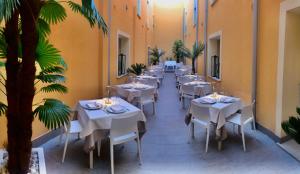 兰佩杜萨Alba D'Amore Hotel & Spa的一间设有白色桌椅的餐厅,并种植了棕榈树