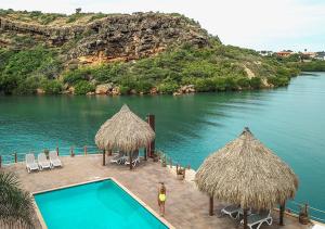 简蒂埃尔库拉索帕拉帕海滩度假酒店的一个带游泳池和稻草遮阳伞的度假村