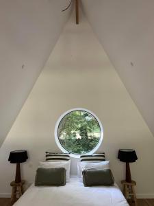 DonnayLa Maison Villeneuve - Lodges avec bains nordiques的一间卧室配有一张带圆形窗户的床